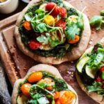 Mini vegan spelt pizzas with spinach pesto, roast tomatoes, courgette & rocket